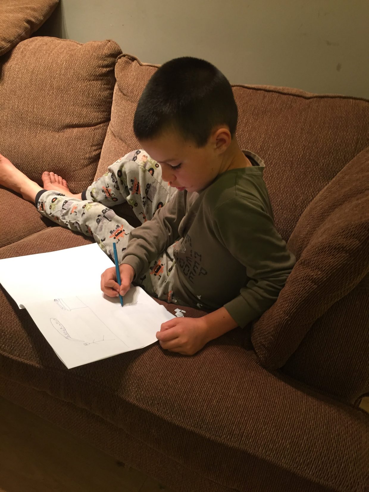 my son writing a story on the couch